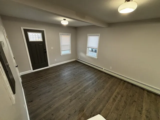 a view of an empty room with window and wooden floor