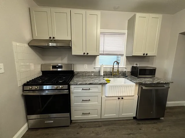 a kitchen with granite countertop white cabinets and stainless steel appliances