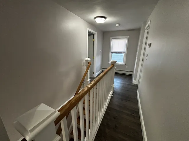 a view of a hallway with wooden floor and staircase