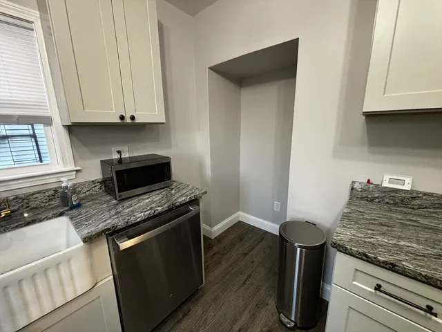 a kitchen with granite countertop a sink stove and cabinets
