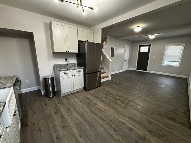 a kitchen with granite countertop a refrigerator stove and wooden floor