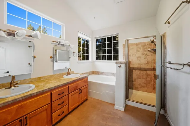 a bathroom with a tub sink vanity granite and shower