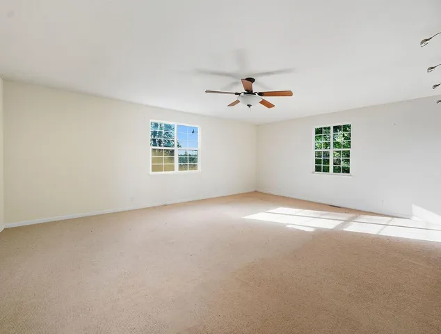 a view of a big room with windows and chandelier fan