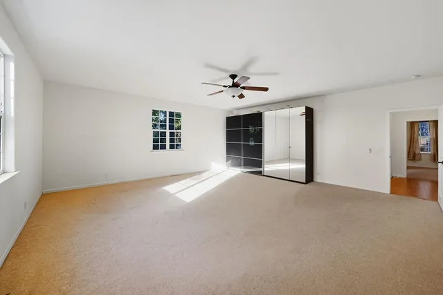 a view of a livingroom with a chandelier fan and windows