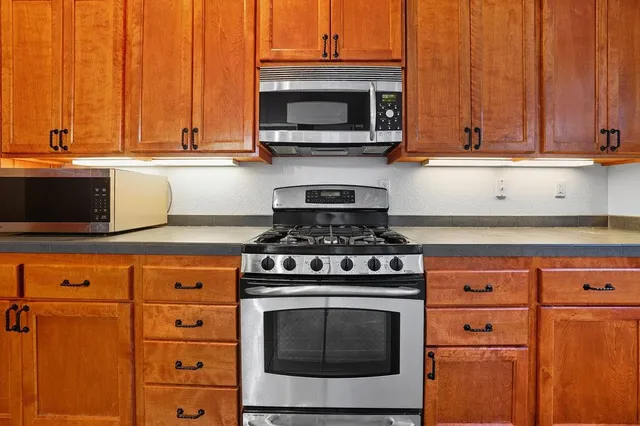 a kitchen with stainless steel appliances granite countertop a stove microwave and cabinets