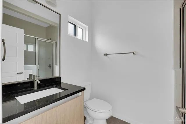 a bathroom with a granite countertop sink toilet and mirror