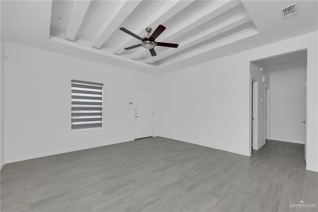 an empty room with wooden floor a ceiling fan and windows