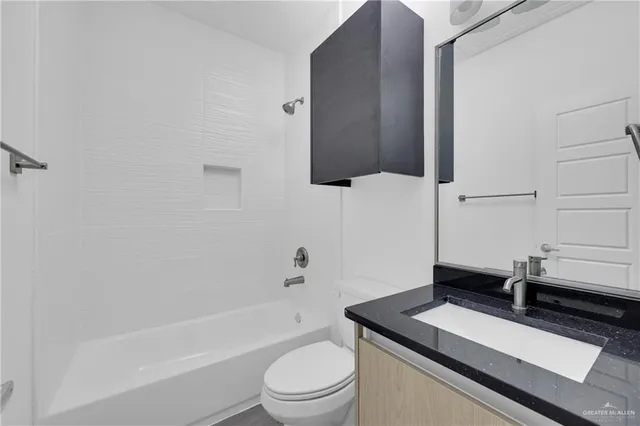 a bathroom with a granite countertop sink toilet a mirror and bathtub