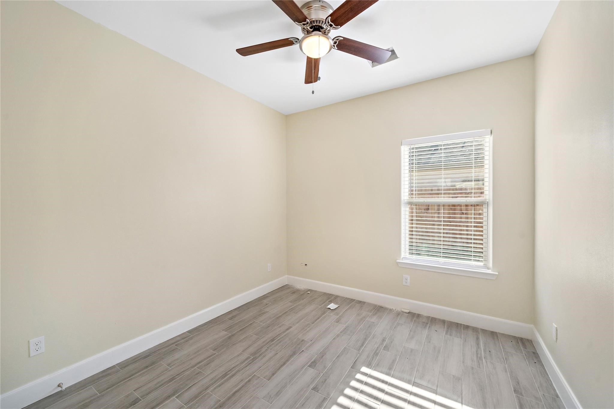 5618 Ridgeway Drive, Unit B Houston, TX 77033 - Photo 5 of 9 This room features neutral walls, a ceiling fan, and a window providing natural light. It has light wood-look tile flooring, offering a modern and clean look.