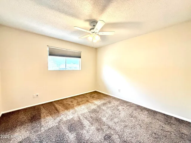 an empty room with a window and a ceiling fan