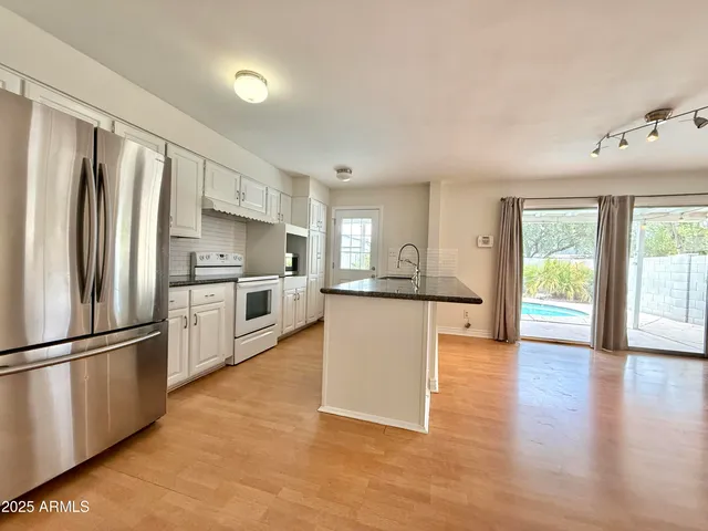 a kitchen with stainless steel appliances granite countertop a refrigerator a stove a sink dishwasher and a refrigerator with wooden floor