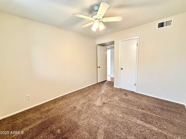 an empty room with windows and fan