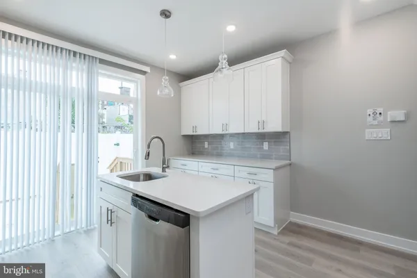 a view of a kitchen with a sink and dishwasher with wooden floor