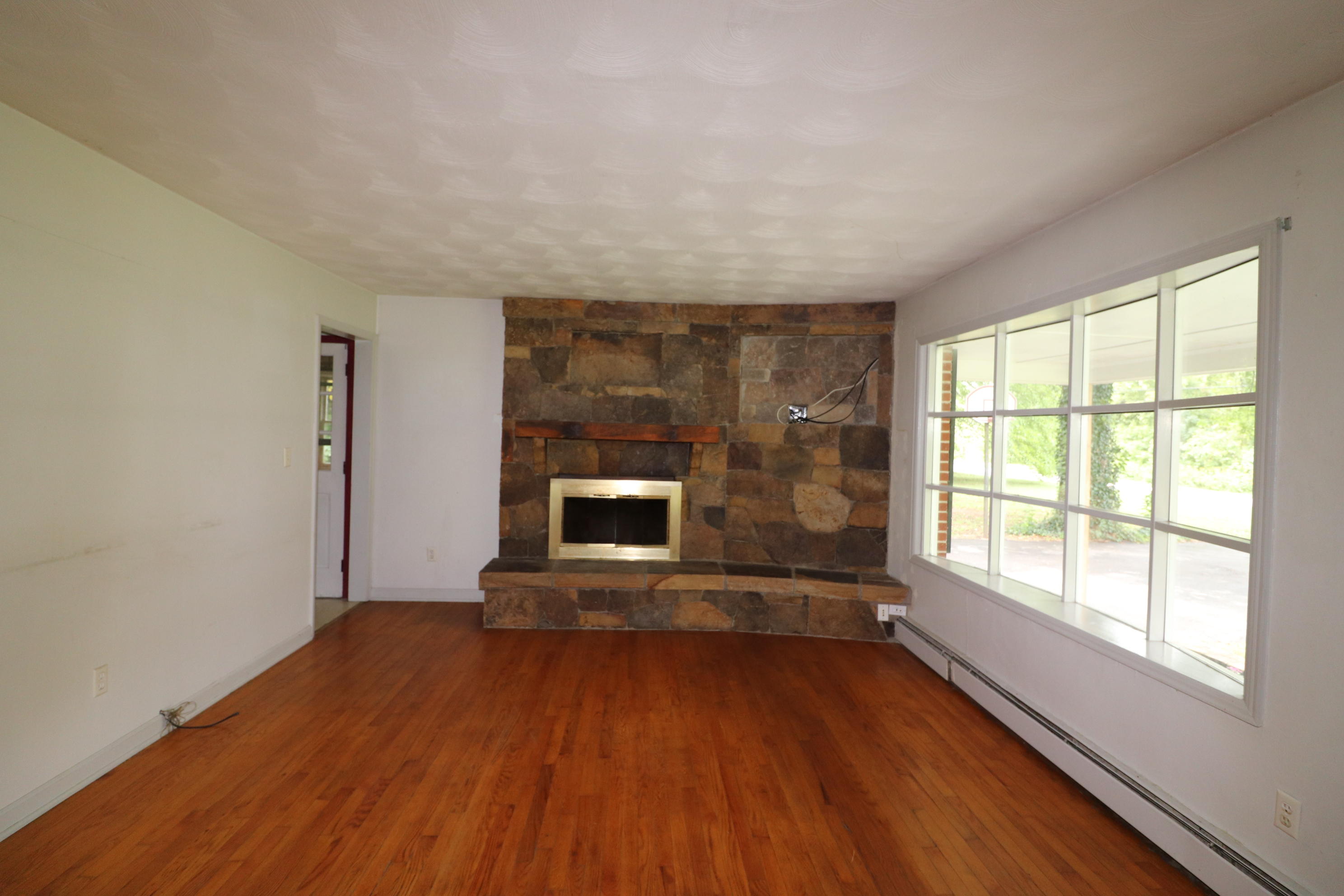 5501 Lafayette Road Elliston, VA 24087 - Photo 7 of 18 an empty room with wooden floor and fireplace