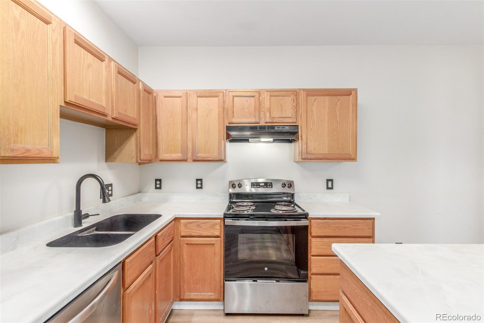 12931 Lafayette Street, Unit G Thornton, CO 80241 - Photo 12 of 21 a kitchen with stainless steel appliances a sink stove and white cabinets