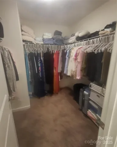 a view of walk in closet with clothes and shoes