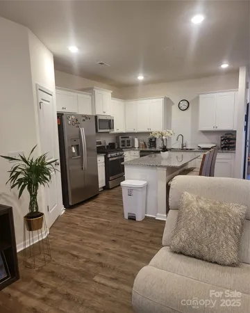a living room with furniture a refrigerator and a dining table with wooden floor