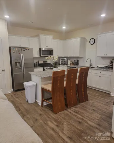 a large kitchen with a table chairs wooden floor and stainless steel appliances
