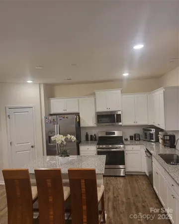 a kitchen with stainless steel appliances a stove a sink a microwave a refrigerator and cabinets
