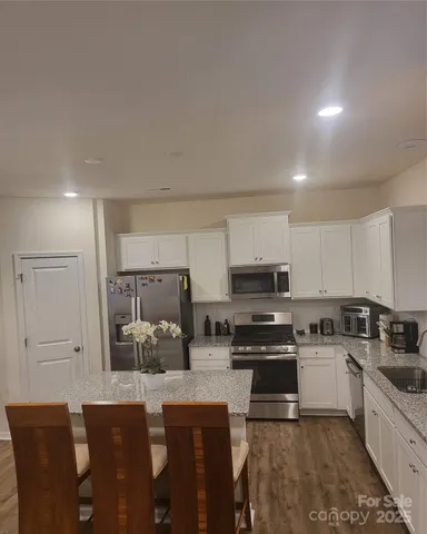 a kitchen with stainless steel appliances a stove a sink a microwave a refrigerator and cabinets