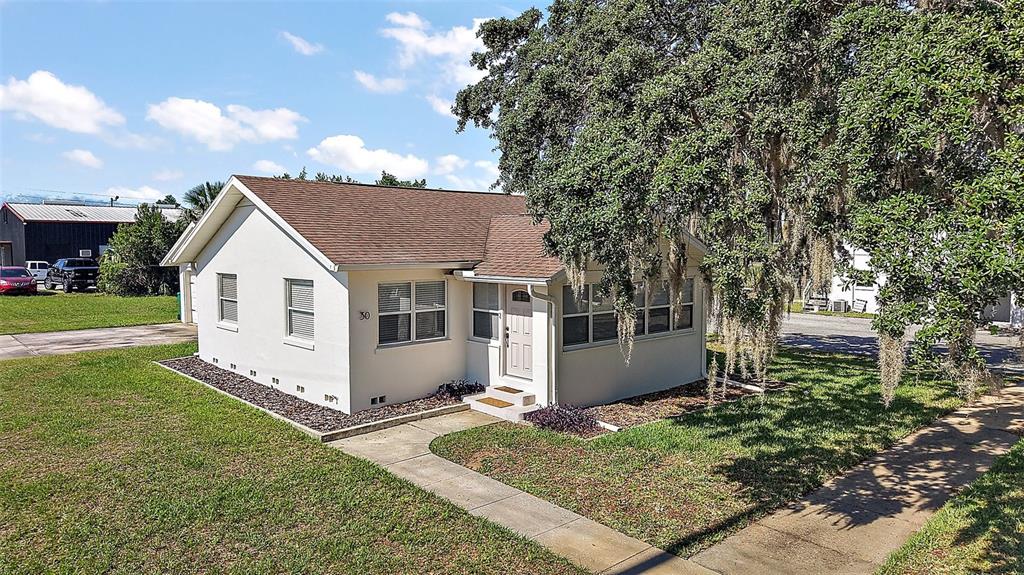 30 East Key Avenue Eustis, FL 32726 - Photo 30 of 32 a view of a white house with a yard and table and chairs under an umbrella