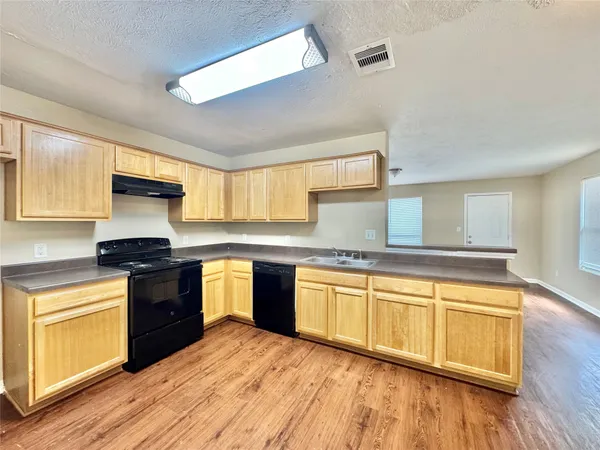 a large kitchen with cabinets wooden floor and stainless steel appliances