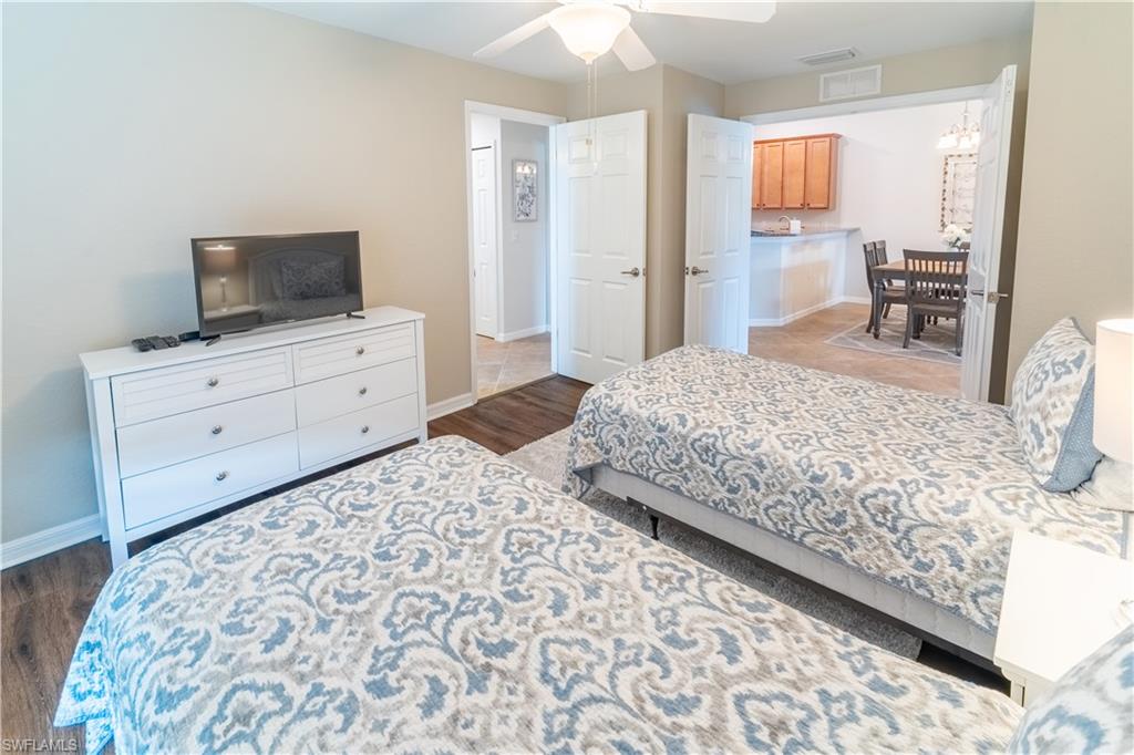 9521 Avellino Way, Unit 2426 Naples, FL 34113 - Photo 13 of 46 a bedroom with a bed and wooden floor