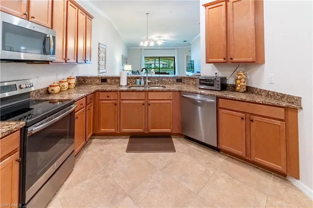 a kitchen with granite countertop a sink stainless steel appliances a window and a counter top space