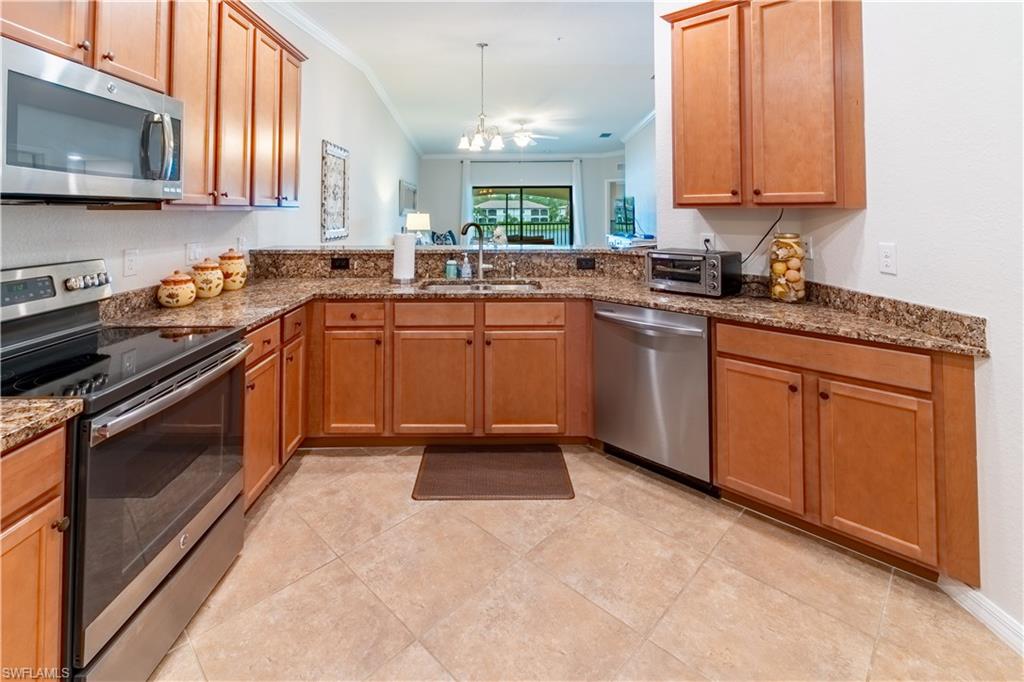 9521 Avellino Way, Unit 2426 Naples, FL 34113 - Photo 6 of 46 a kitchen with granite countertop a sink stainless steel appliances a window and a counter top space