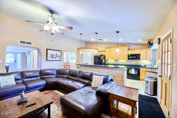 a living room with furniture kitchen view and a chandelier