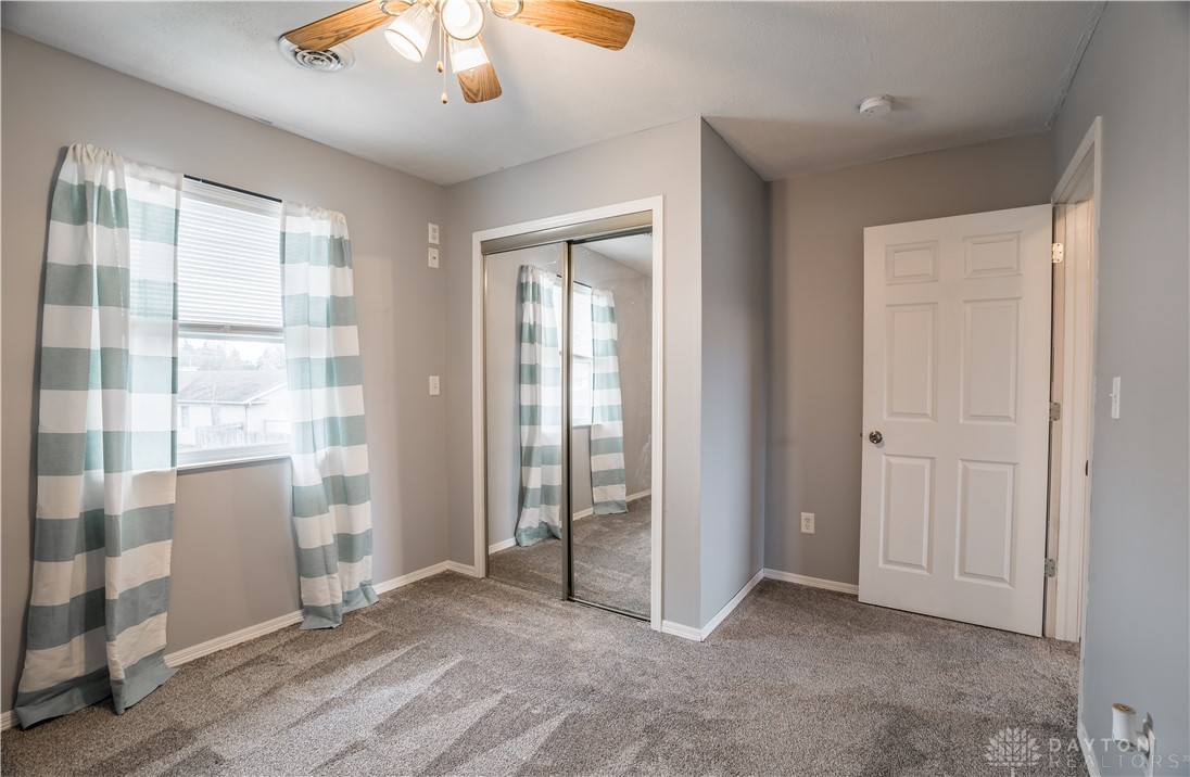1442 Langdon Road Sidney, OH 45365 - Photo 22 of 34 This cozy bedroom features a ceiling fan, plush carpet, and a convenient mirrored closet.