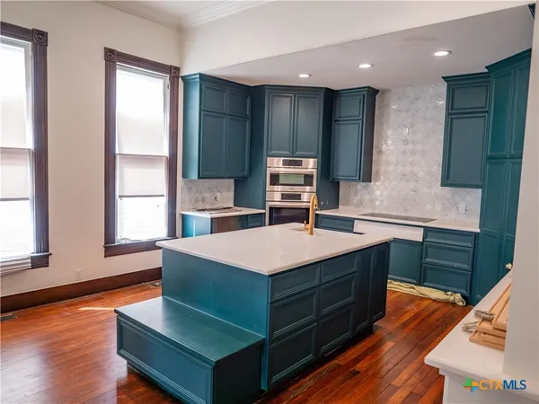 a kitchen with stainless steel appliances kitchen island granite countertop a refrigerator and a sink