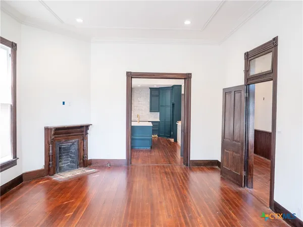 an empty room with wooden floor windows and two windows