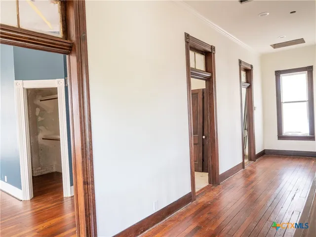 a view of an empty room with a window and wooden floor