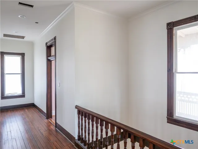 a view of a hallway with wooden floor and a bathroom