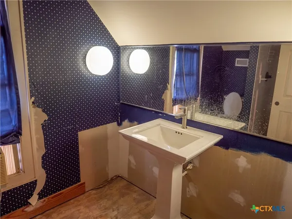 a view of a hallway with wooden floor and a bathroom