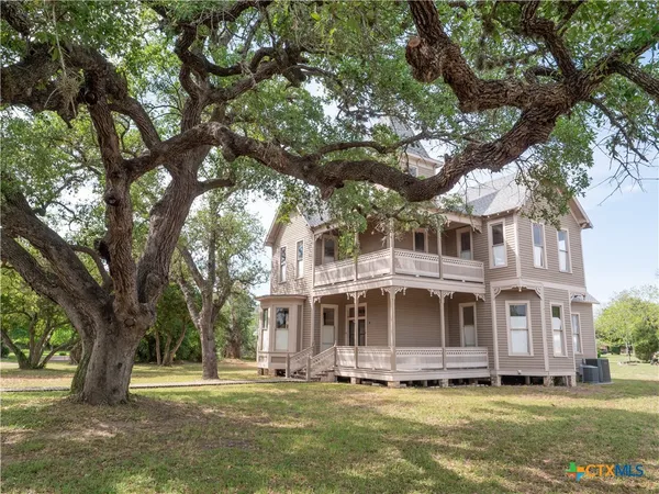 a front view of a house with a garden and trees