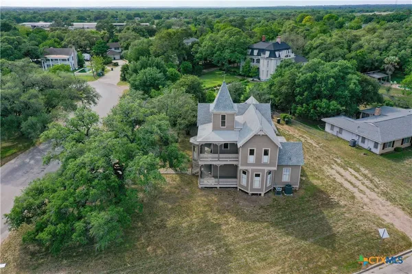 an aerial view of a house with a big yard and large trees