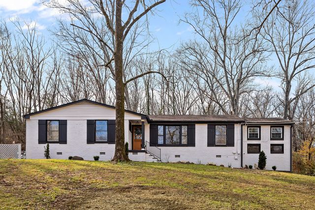 a front view of a house with a garden and tree