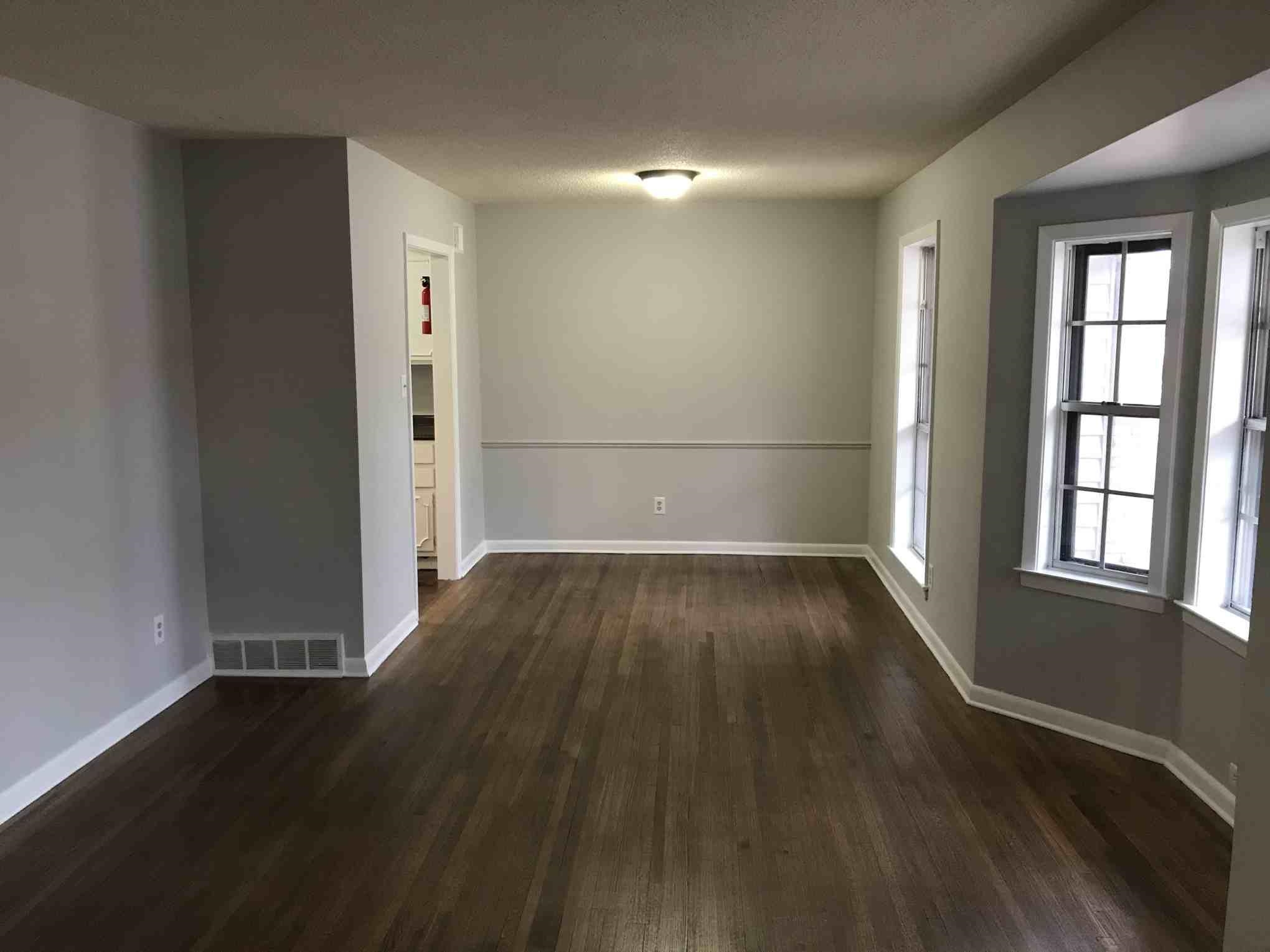 4502 Cottonwood Road Memphis, TN 38118 - Photo 9 of 16 Spacious room featuring wood-finish flooring, light grey painted walls with chair rail molding, white baseboards, and a bay window configuration with multiple windows