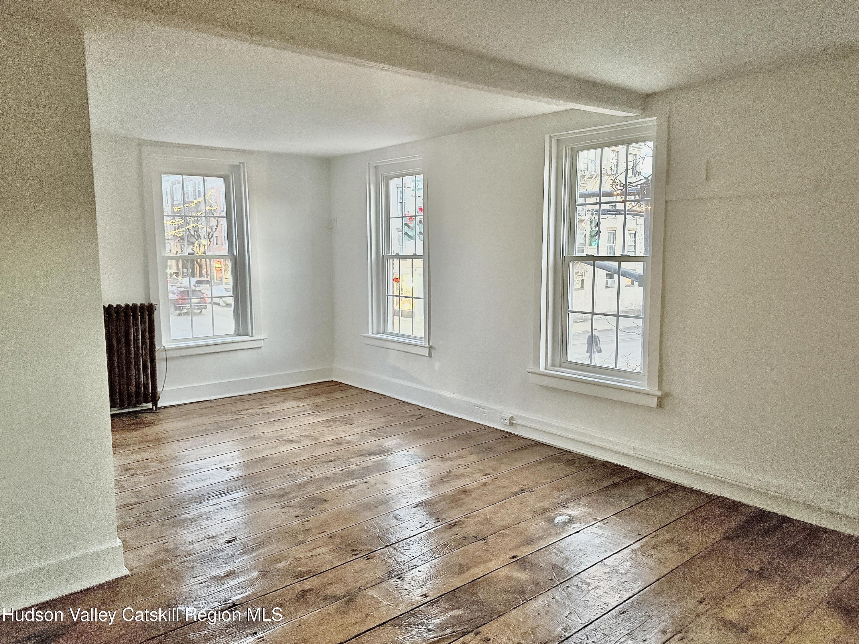 624 Warren Street, Unit 2 Hudson, NY 12534 - Photo 4 of 8 an empty room with wooden floor and windows