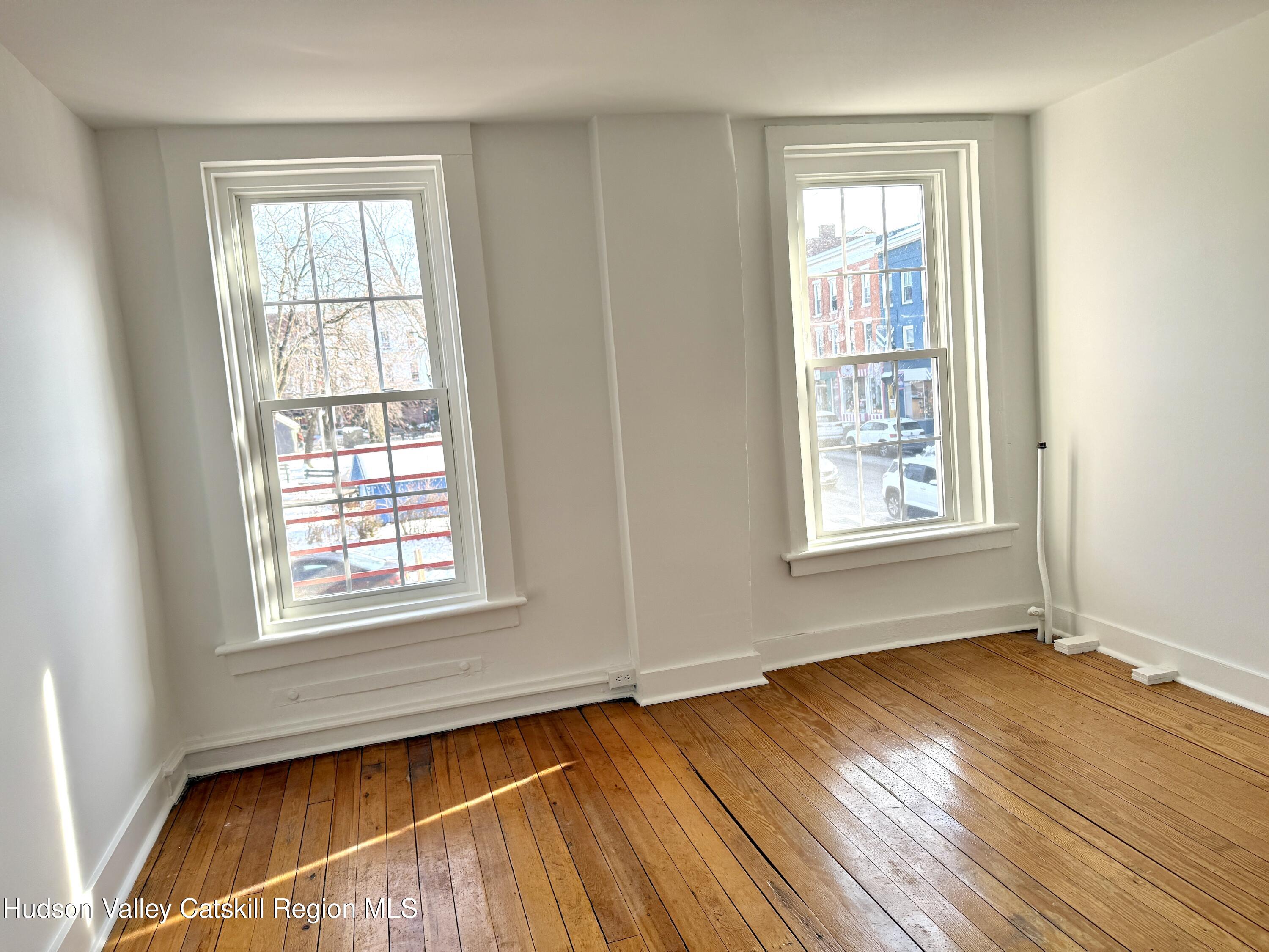 624 Warren Street, Unit 2 Hudson, NY 12534 - Photo 6 of 8 an empty room with wooden floor and windows