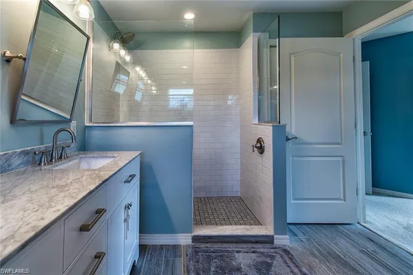 a bathroom with a granite countertop sink a mirror and shower