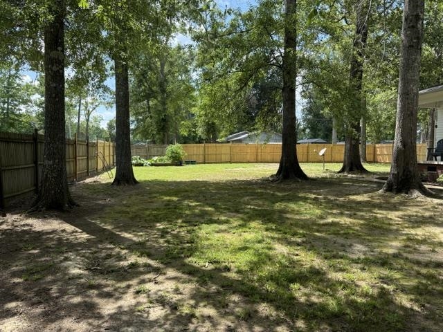 395 Austin Street Savannah, TN 38372 - Photo 21 of 32 Expansive backyard featuring a natural grass lawn, mature trees, and a wooden privacy fence