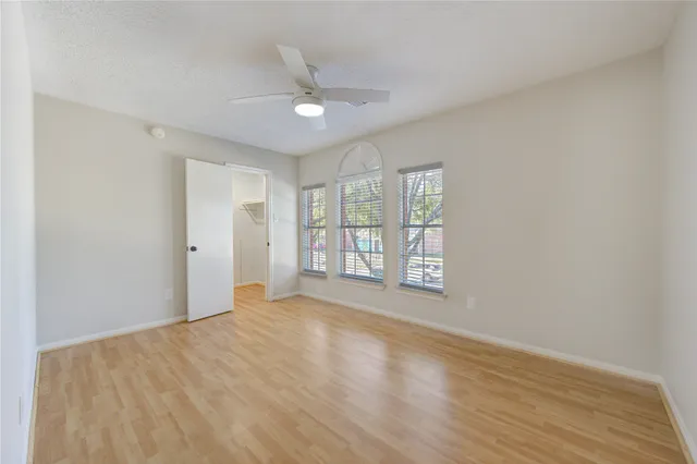 a view of an empty room with a window and wooden floor
