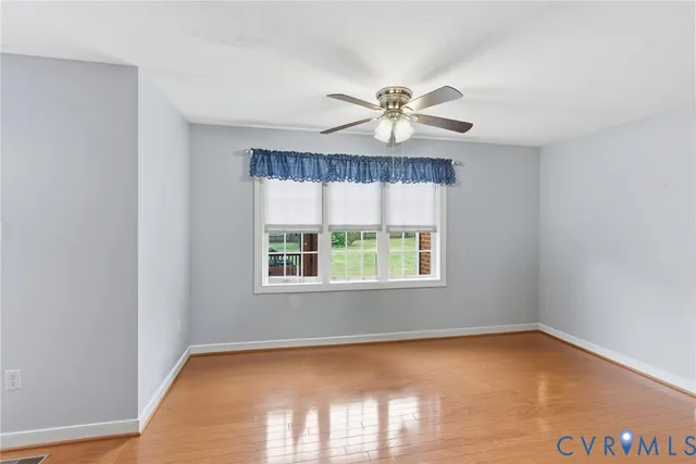 an empty room with a window and a fan
