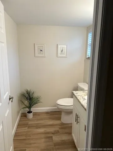 a bathroom with a toilet a sink and wooden floor