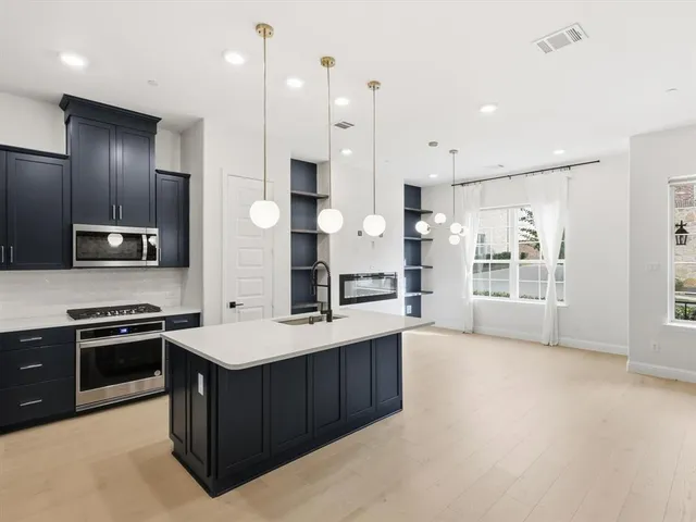 a large kitchen with stainless steel appliances kitchen island granite countertop a stove a sink dishwasher and a refrigerator with wooden floor