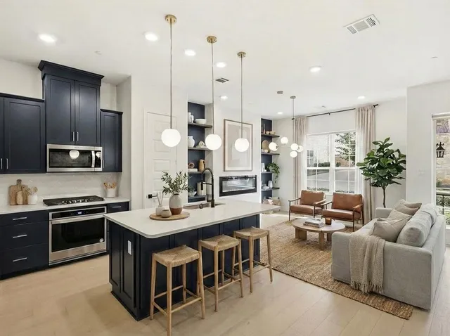 a large kitchen with stainless steel appliances a stove a sink a oven a dining table and chairs