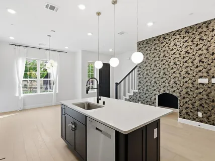 a kitchen with a sink a large island with wooden floor